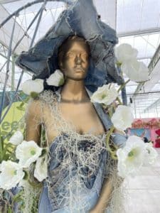 Schaufensterpuppe mit Blumen geschmückt, steht in der Messehalle der Gartenbauausstellung