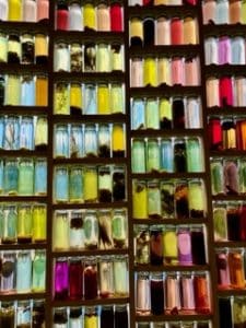 750 Flaschen in allen Farben, gefüllt mit Wasser, Wolle und Pflanzen, die zeigen, wie natürlich und mit Sonnenlicht und Wärme gefärbt werden kann